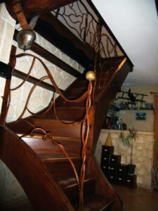 Rampe et garde corps en fer forgé oxydé, vernis installé sur un escalier en bois